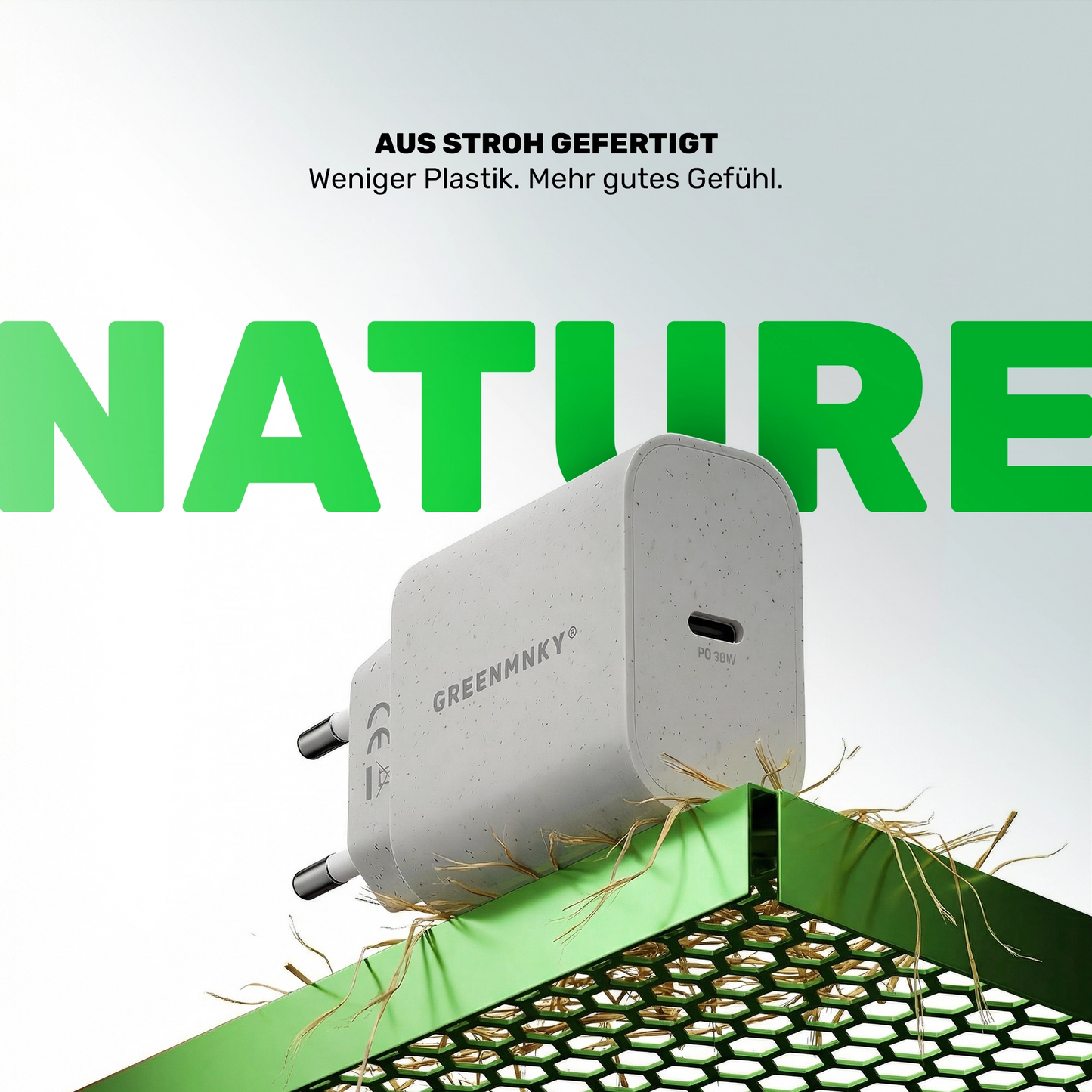 Strohfarbenes GREENMNKY Ladegerät mit einem USB C Port auf grünem Gitter, oben der Text Aus Stroh gefertigt und groß das grüne Wort NATURE