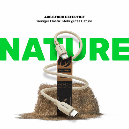 Strohfarbenes Ladekabel mit GREENMNKY Verpackung vor Strohballen, Anschlüsse Lightning und USB C, oben der Text Aus Stroh gefertigt und groß das grüne Wort NATURE